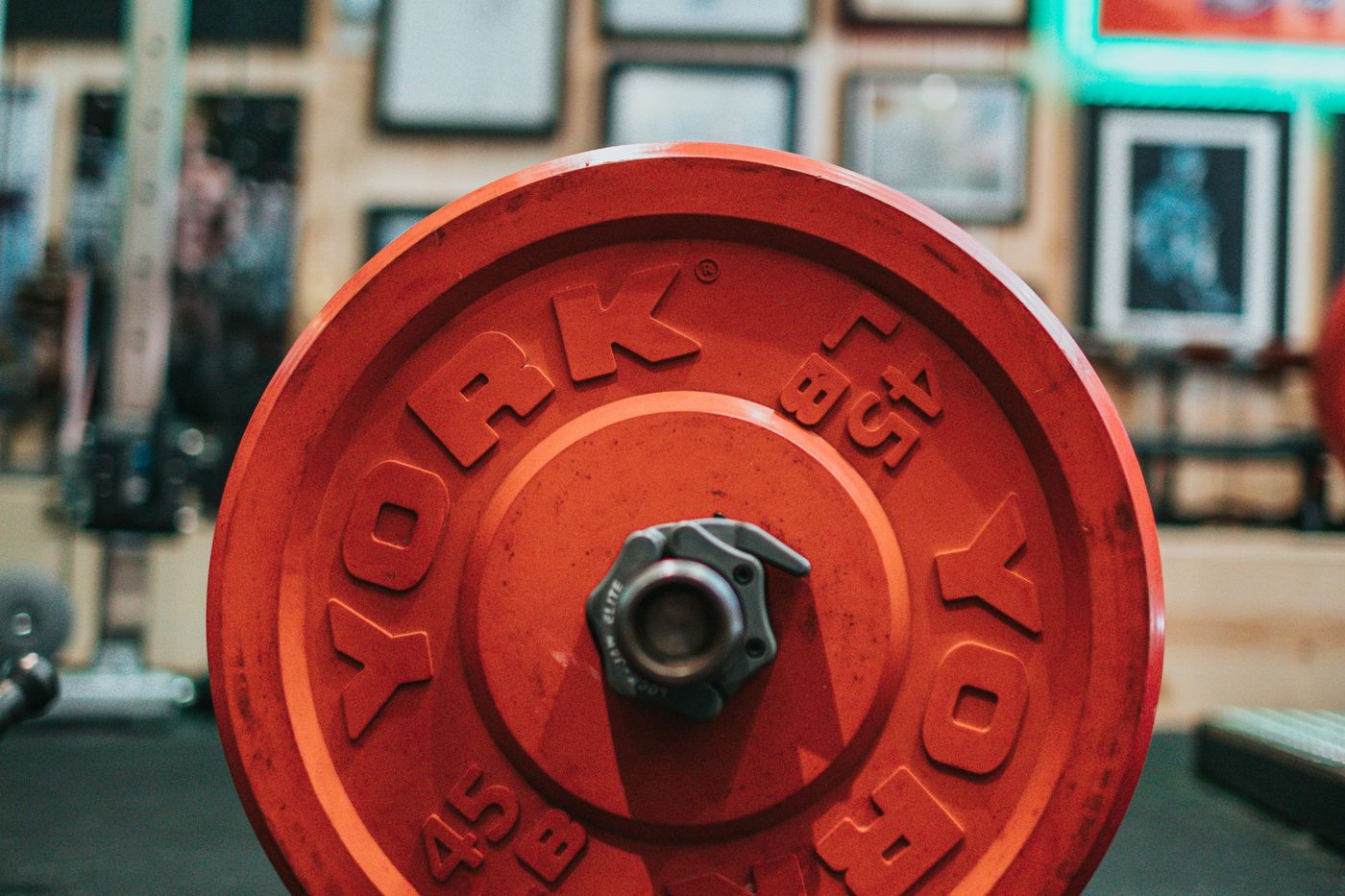 A red weight plate on a barbell in a gym